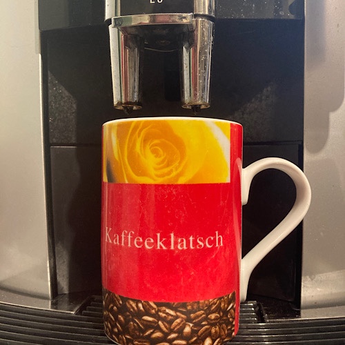 Kaffeebecher fröhlichem rot-gelb mit der Aufschrift "Kaffeeklatsch" auf Kaffeevollautomat