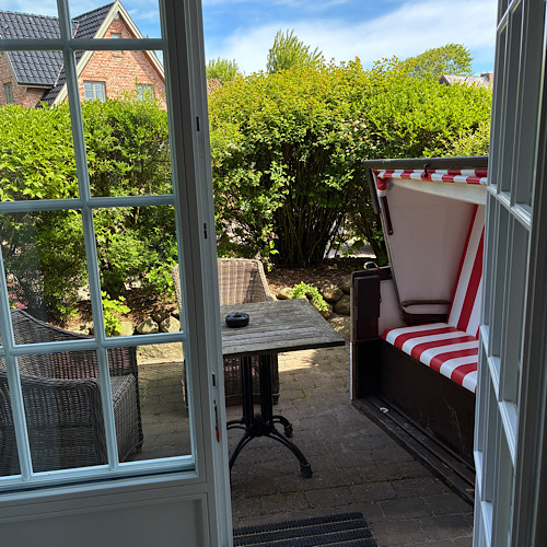 img 2025 05 18 120348 Geöffnete Terrassentür zu einem gemütlichen Garten mit Strandkorb